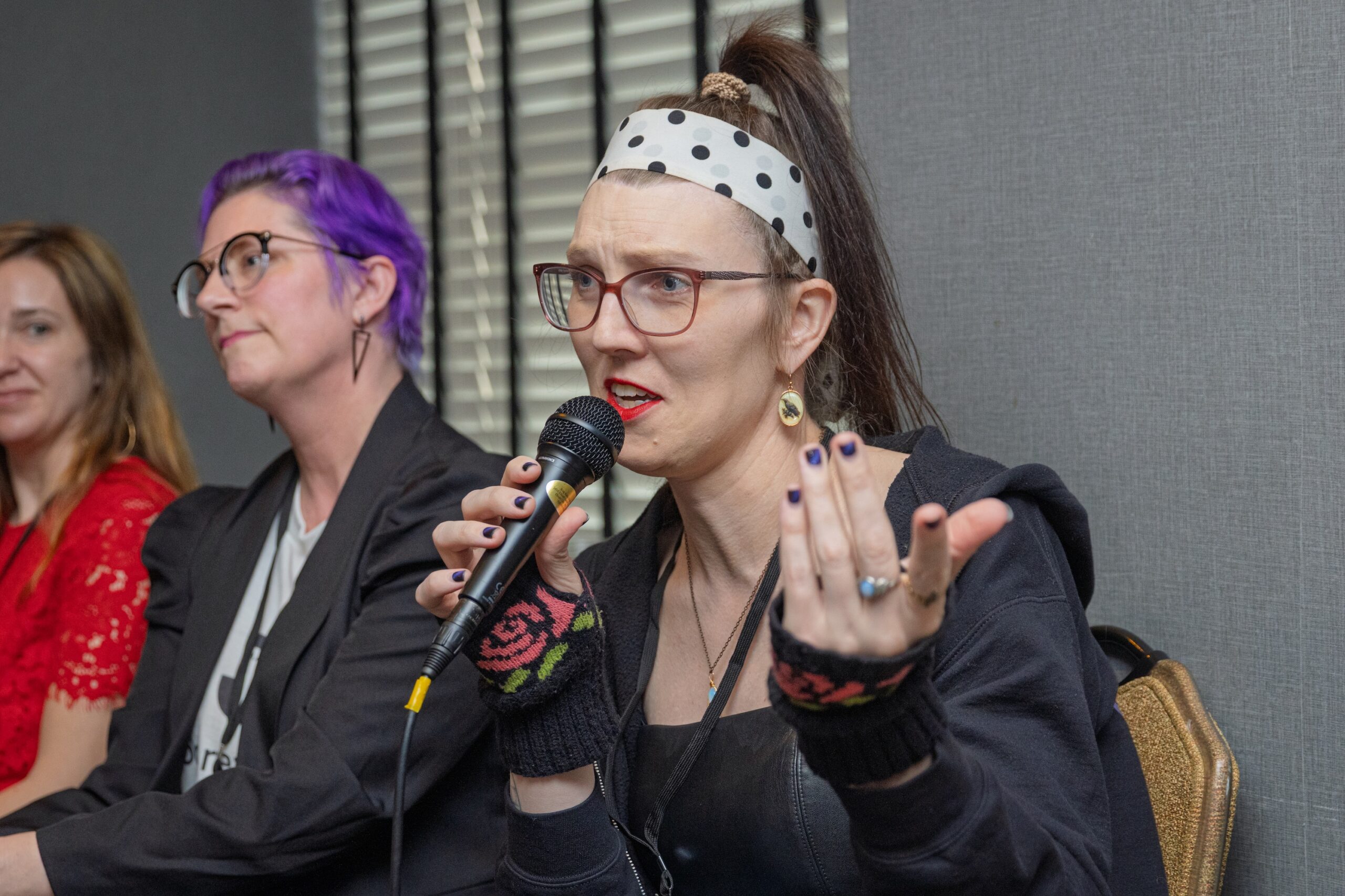 Casey gestures with one hand as she holds the microphone in the other.
